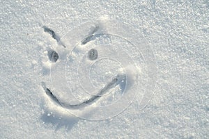 Face of an insidious, angry, smiley, painted on the snow on a sunny winter day. Copy space. Top view.