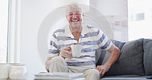 Face, laugh and senior man with coffee on sofa relax, free and chilling at home on weekend. Happy, portrait and elderly