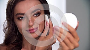Face makeup. Woman applying powder on skin with sponge closeup