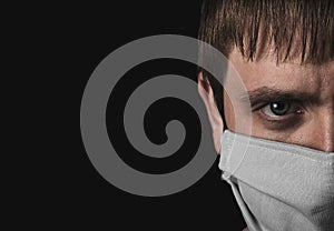 Face of a man in a medical protective mask close-up on a black background. Ð¡oronavirus epidemic.