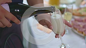 without a face. A man pours champagne into a glass.