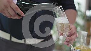 without a face. A man pours champagne into a glass.