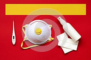 Face mask, bottle with hand sanitizer and thermometer on red background photo