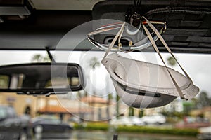 Face mask clipped with sunglasses on visor of interior of a car in a shopping center parking lot during the Coronavirus pandemic