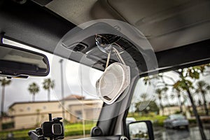 Face mask clipped with sunglasses on visor of interior of a car in a shopping center parking lot during the Coronavirus pandemic