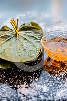 Face mask for controlling oiliness consisting of betel leaves, honey, sea-salt on a black wooden surface.