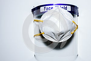 A face mask covered on a face shield placed on a white surface. To use for personal protection against covid 19