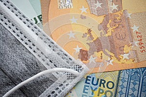 Face mask on Euro banknotes bill background. Global novel coronavirus Covid-19 outbreak effect to EU, world economy, financial