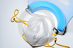 A face mask and a face shield placed on a white surface. To use for personal protection against covid 19