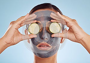 Face mask, skincare and woman with cucumber on eyes for beauty in studio isolated on a blue background. Cosmetics, model