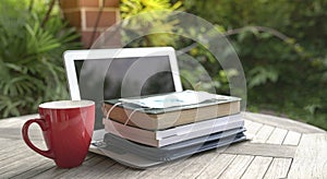 Face mask on top of stacked books and open computer laptop with red cup