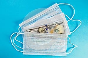 Face masks and banknote of 100 dollars on blue background. Concept of deficit, speculation and sold out of medical masks