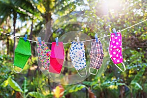Face masks with different style prints hang and dry on clothespins outdoors at sunset