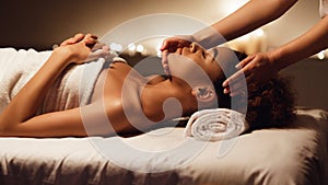 Face massage. African-american woman getting spa treatment