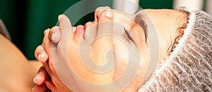 Face massage. Beautiful caucasian young white woman having a facial massage with closed eyes in a spa salon.