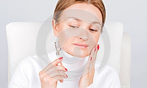 Face massage. Beautiful woman getting massage face using roller massage
