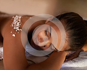 Face, massage and salt with woman at spa on bed or table for luxury pamper treatment or exfoliation. Beauty, peace or