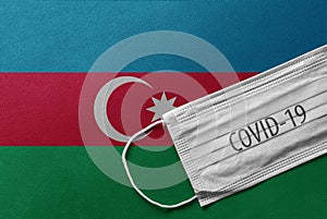 Face Medical Surgical White Mask with COVID-19 inscription lying on Azerbaijan National Flag. Coronavirus in Azerbaijan