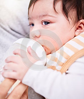 Face, milk and a baby drinking from a bottle closeup with a parent for health, diet or nutrition. Food, formula or