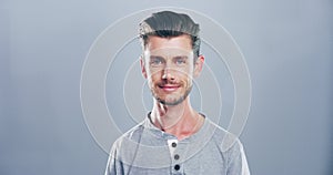 Face, model or happy man in studio with smile or mockup space isolated on gray background. Funny, casual style or