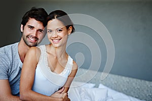 The face of newly-weds. Portrait of a happy couple sitting on their bed with copyspace.