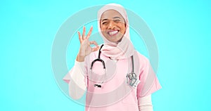 Face, nurse and Muslim woman with ok sign in studio isolated on blue background mockup. Smile, portrait and happy