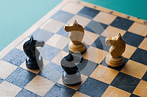 Face Off. Chess pieces knights facing each other for a standoff on chessboard with blue background.