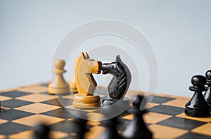 Face Off. Chess pieces knights facing each other for a standoff on chessboard with blue background.