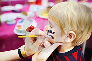 Face painting for cute little boy during kids birthday party