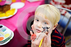 Face painting for cute little boy during kids birthday party