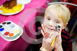 Face painting for cute little boy during kids birthday party