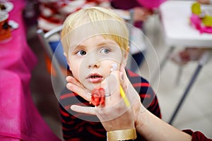 Face painting for cute little boy during kids birthday party