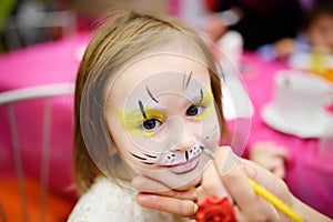 Face painting for cute little girl during kids birthday party