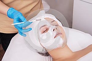 Face peeling mask, spa beauty treatment, skincare. Woman getting facial care by beautician at spa salon