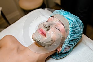 Face peeling mask, spa beauty treatment, skincare. Woman getting facial care by beautician at spa salon..