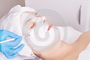 Face peeling mask, spa beauty treatment, skincare. Woman getting facial care by beautician at spa salon