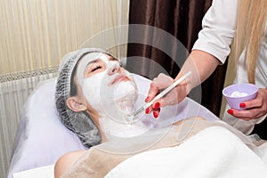 Face peeling mask, spa beauty treatment, skincare. Woman getting facial care by beautician at spa salon