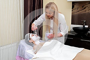 Face peeling mask, spa beauty treatment, skincare. Woman getting facial care by beautician at spa salon