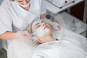 Face peeling mask, spa beauty treatment, skincare. Woman getting facial care by beautician at spa salon.