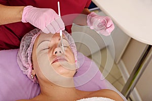 Face peeling mask, spa beauty treatment, skincare. Woman getting facial care by beautician at spa salon