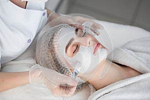 Face peeling mask, spa beauty treatment, skincare. Woman getting facial care by beautician at spa salon.