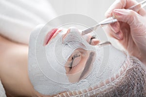 Face peeling mask, spa beauty treatment, skincare. Woman getting facial care by beautician at spa salon.