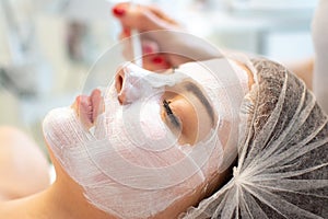 Face peeling mask, spa beauty treatment, skincare. Woman getting facial care by beautician at spa salon, close-up.