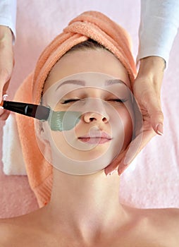 Face peeling mask, spa beauty treatment, skincare. Woman getting facial care by beautician at spa salon, side view