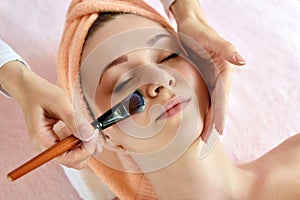 Face peeling mask, spa beauty treatment, skincare. Woman getting facial care by beautician at spa salon, side view, close-up