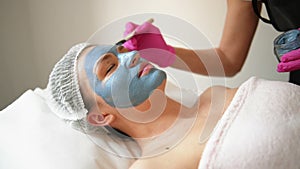 Face peeling mask, spa beauty treatment, skincare. Woman getting facial care by beautician at spa salon. Woman makes an