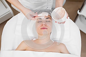 Face peeling mask, spa beauty treatment, skincare. Woman getting facial care by beautician at spa salon. Woman makes an