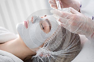 Face peeling mask, spa beauty treatment. Woman getting facial care by beautician at spa salon