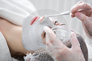 Face peeling mask, spa beauty treatment. Woman getting facial care by beautician at spa salon.