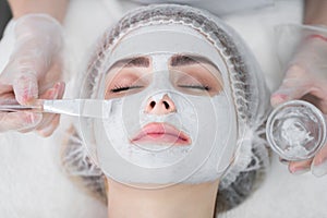 Face peeling mask, spa beauty treatment. Woman getting facial care by beautician at spa salon.